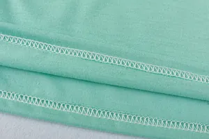 Detailed close-up showing professional flatlock stitching on mint green knit fabric