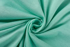 Macro view of soft mint green jersey knit fabric texture with a smooth spiral drape