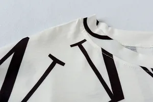 Detailopname van de halslijn en stiksels op een witte loungewear top met letterprint.