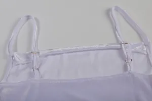 Detailansicht der verstellbaren Schultergurte eines weißen Samtkleid-Camisoles mit Metallschnallen.