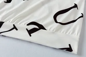 Detailopname van witte stof met zwarte letterprint en elastische tailleband