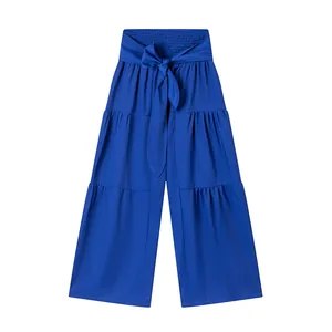 Détail du pantalon large à taille haute bleu roi avec ceinture à nœud et volants.