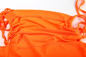 Close-up detail of orange halter neck dress fabric showing fine stitching and gathers.