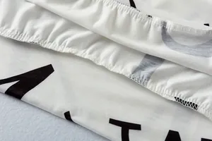 Detail van de elastische zoom en stiksels op een wit vrijetijdssetje met letterprint