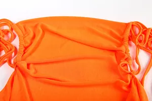 Detailed macro view of an orange halter dress featuring ruched sides and drawstring ties.