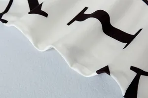 Macro-opname van zachte witte stof met gedurfde zwarte letterprint en textielstructuur