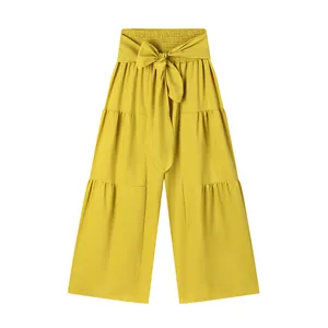 Détail d'un pantalon large jaune moutarde avec taille haute élastiquée et nœud frontal