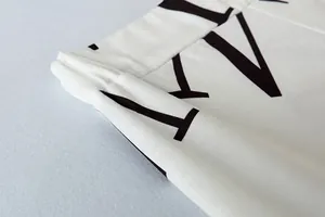 Macrodetail van de elastische tailleband en letterprint van de witte vrijetijdsbroek.