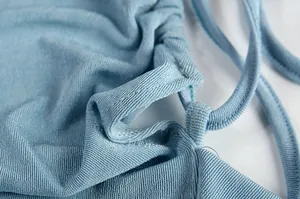 Macro detail of blue ribbed fabric texture and stitching on a halter maxi dress.