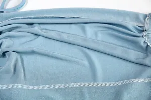 Detailed view of light blue ribbed dress fabric showing double-stitched hem and texture.