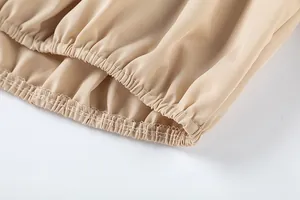 Détail de l'ourlet élastiqué sur un pantalon beige à taille haute et jambe large.