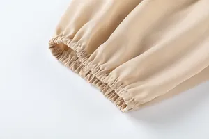 Vue rapprochée du détail de l'ourlet élastique sur ce pantalon beige à taille haute