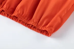 Vue détaillée de la taille élastique froncée sur un pantalon orange à taille haute