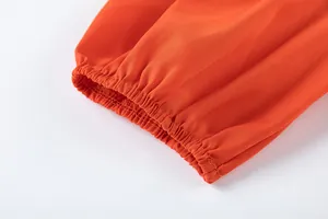 Détail de l'ourlet élastiqué d'un pantalon large orange montrant la texture du tissu