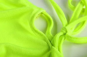 Close-up detail of neon green ribbed fabric with halter neck strap and stitching.
