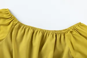 Détail du décolleté d'un haut jaune à épaules dénudées avec des plis élastiques fins