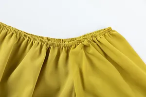Détail en gros plan de la taille haute élastiquée du pantalon large jaune fluide