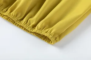 Vue macro détaillée de l'ourlet élastiqué sur le pantalon large jaune moutarde