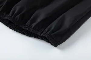 Détail en gros plan du bord élastiqué et du tissu froncé sur ce pantalon noir large