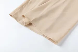 Gros plan de l'ourlet d'un pantalon large beige montrant des coutures fines et un tissu fluide.