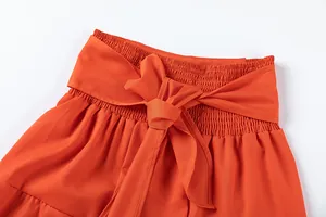 Gros plan sur le pantalon orange à taille haute avec taille élastiquée et nœud décoratif