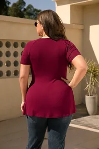 Back view of a plus-size women's burgundy short sleeve tunic top in a sunny outdoor setting