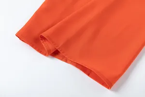 Gros plan de l'ourlet du pantalon large orange montrant la texture du tissu et couture