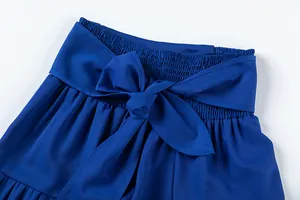 Détail d'un pantalon bleu à taille haute élastiquée avec une grande ceinture à nœud.