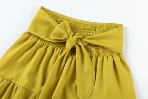 Détail du pantalon large jaune taille haute avec une élégante ceinture élastique nouée