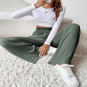 Casual style shot of woman wearing green ribbed knit wide-leg pants and a white crop top.