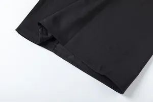 Gros plan détaillé des coutures de l'ourlet d'un pantalon large noir à taille haute.