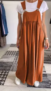 Full-length view of woman in burnt orange cotton linen pinafore dress over white tee