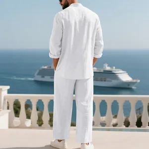 Vista posterior de hombre con conjunto de lino blanco en un balcón frente al mar.