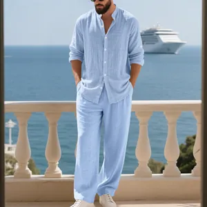 Modelo con camisa de lino azul claro de cuello mao y pantalón ancho en un balcón al mar.
