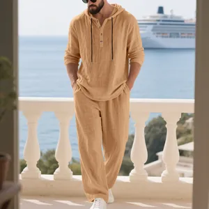 Men's tan linen 2-piece hoodie and pants set shown in a relaxed seaside setting.