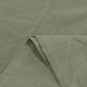 Détail rapproché du tissu en lin vert olive montrant le tissage et les coutures
