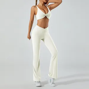 Détail d'un ensemble de yoga blanc avec brassière de sport et pantalon évasé taille haute.