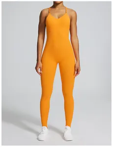 Full body view of a vibrant orange seamless yoga jumpsuit on a fit model in a studio