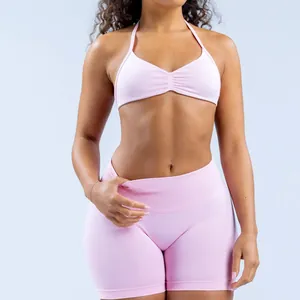 Detailed view of pink seamless halter neck sports bra and yoga shorts on model.