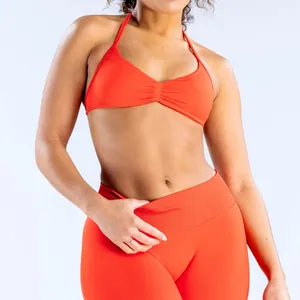 Naadloze oranje yogaset met halter sport-bh en fitnesslegging met een hoge taille