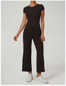 Vista completa di una donna con top da yoga nero a maniche corte e pantaloni larghi