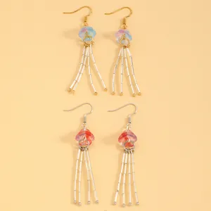 Vue macro de deux paires de boucles d'oreilles à pompons style océan avec perles fleurs.