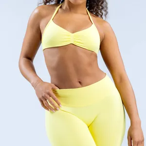 Detail van naadloze gele yogaset met halterbeha en legging met hoge taille