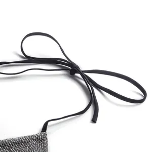 Macro view of black tie straps and glittering silver rhinestone texture on bikini top