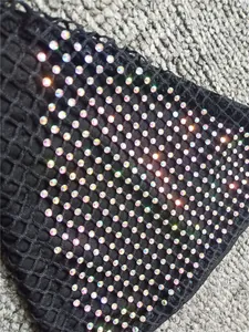 Vue détaillée macro de strass AB étincelants sur un tissu de bikini sexy en résille noire.