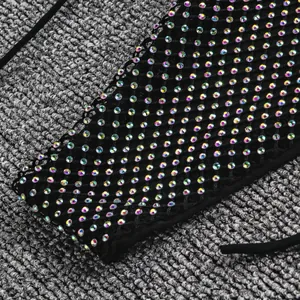Détail macro montrant des strass irisés étincelants sur un tissu de bikini en maille noire.