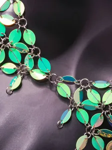Detailed close-up showing iridescent green leaf sequins connected by silver metal rings