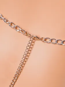 Macro detail view of a silver metal body chain showing lobster clasp and oval link structure