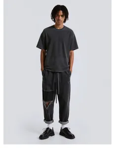 Full body view of a man in a vintage washed grey t-shirt and distressed pants