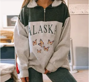 Close-up of Alaska and butterfly print detail on a two-tone oversized half-zip sweatshirt